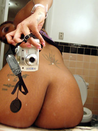 Tattoed young ebony taking pictures of